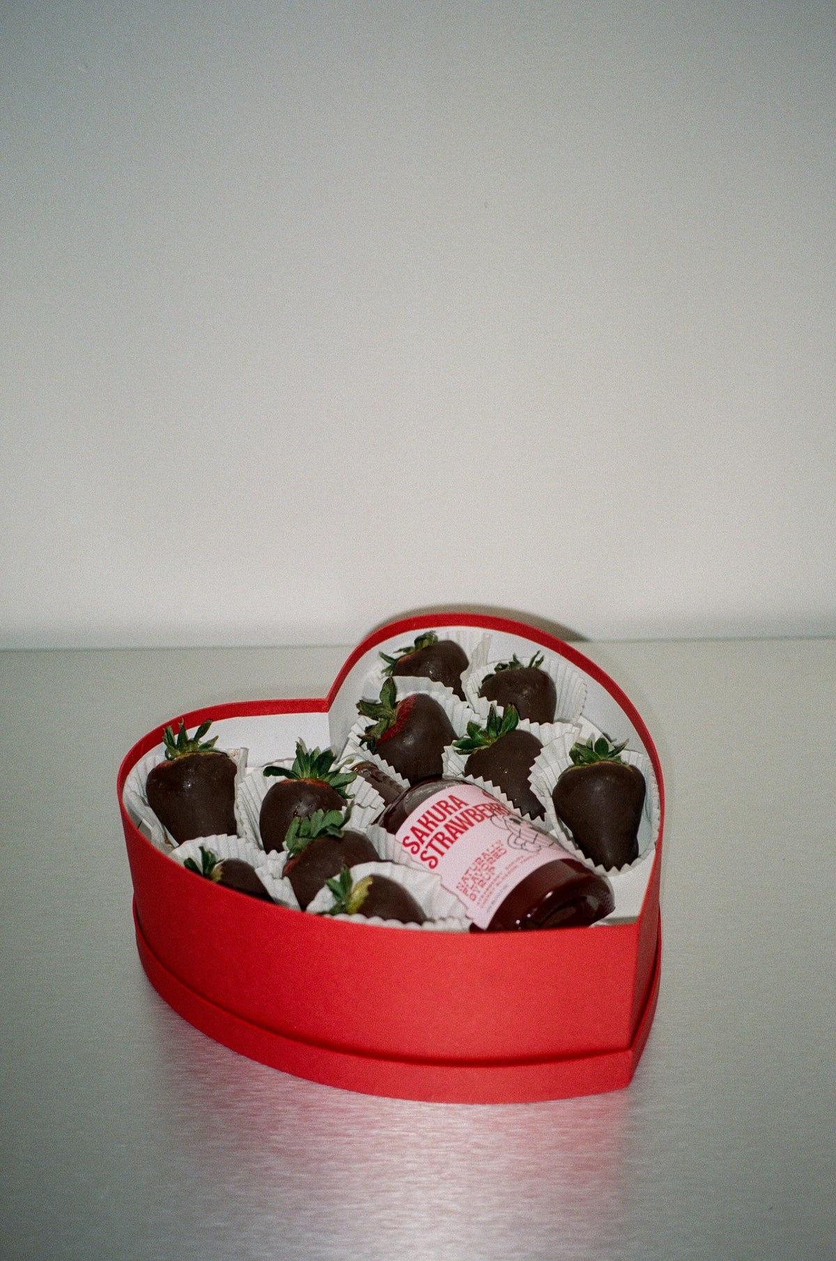 Heart-shaped box of chocolate-covered strawberries on a plain background
